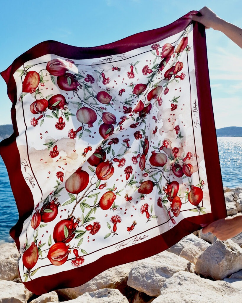 Fosca dalmatica Luksuzna svilena marama Fosca Dalmatica s autorskim ilustriranim motivom nara (šipka) na podlozi inspiriranoj Mediteranom.